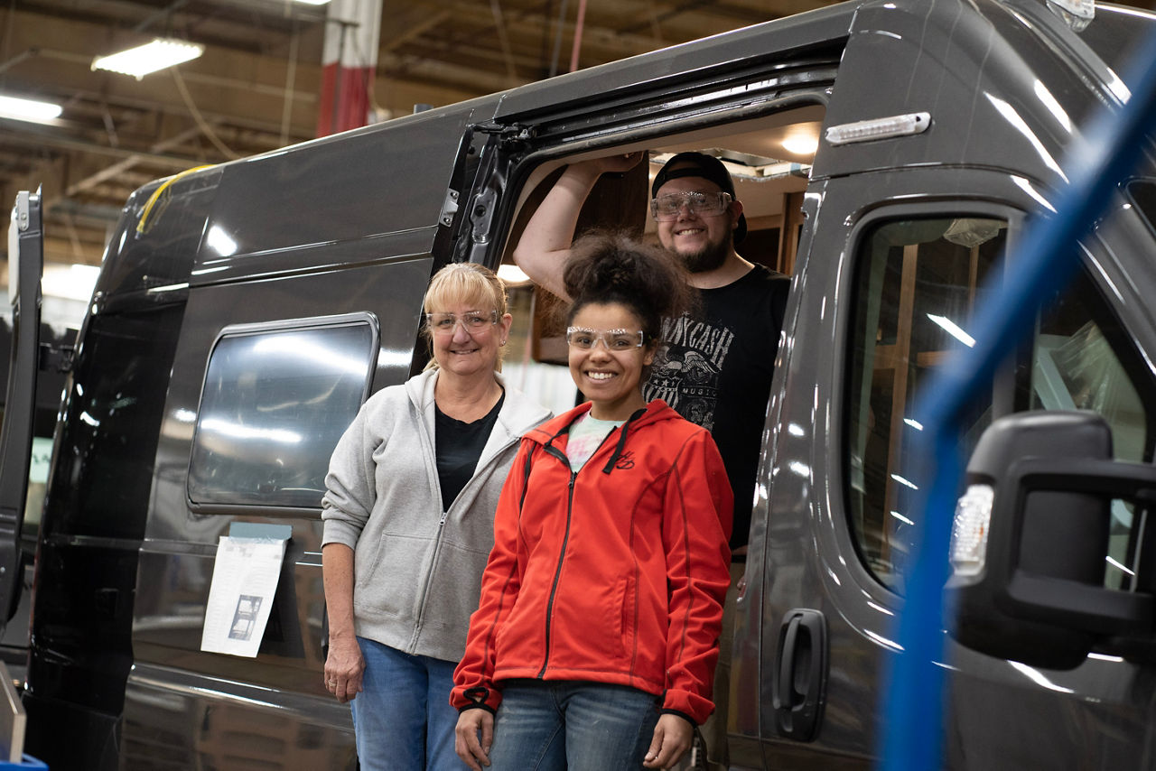 Winnebago workers posing outside of vehicle