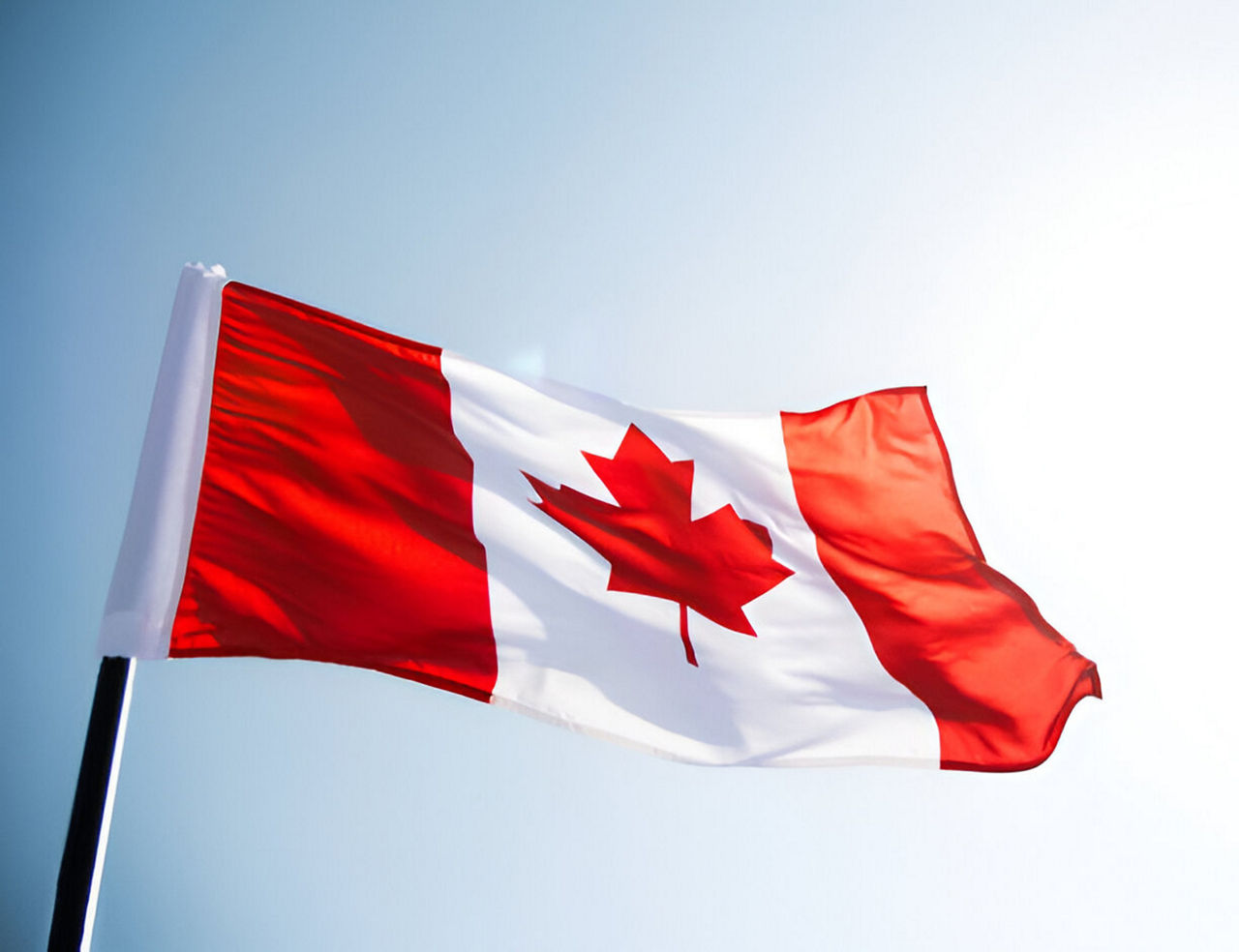 Canadian flag waving against clear blue sky
