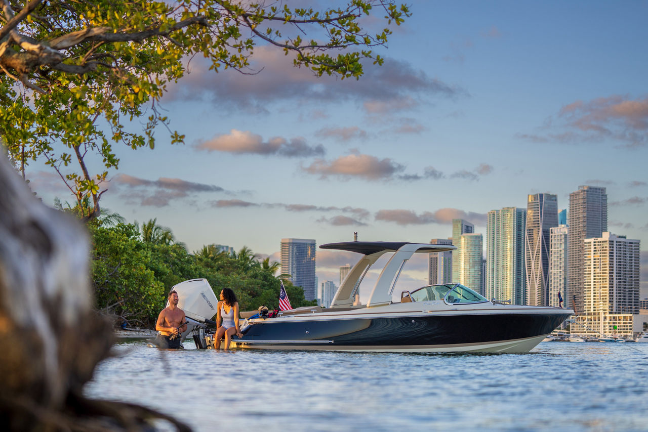 Couple sitting on back of Chris Craft boat looking at bridge