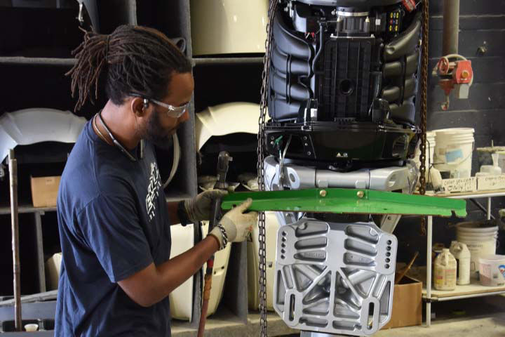 Chris Craft Employee working on a large metal boat part