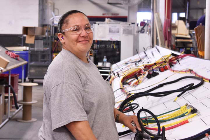 Chris Craft Employee smiling while standing in front of some parts and blueprints