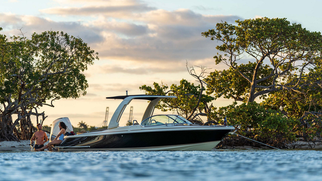 Launch 25 GT boat on the water with trees behind it