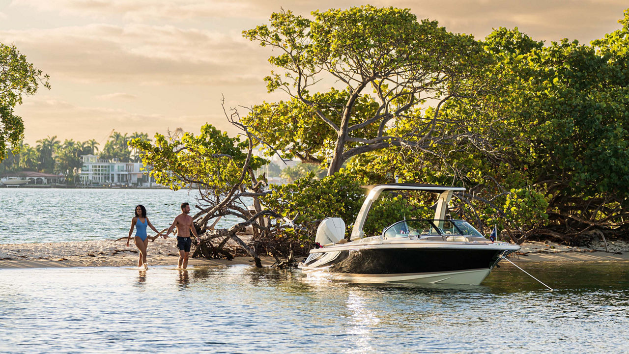 Launch 25 GT boat on the shore with two people holding hands walking towards it