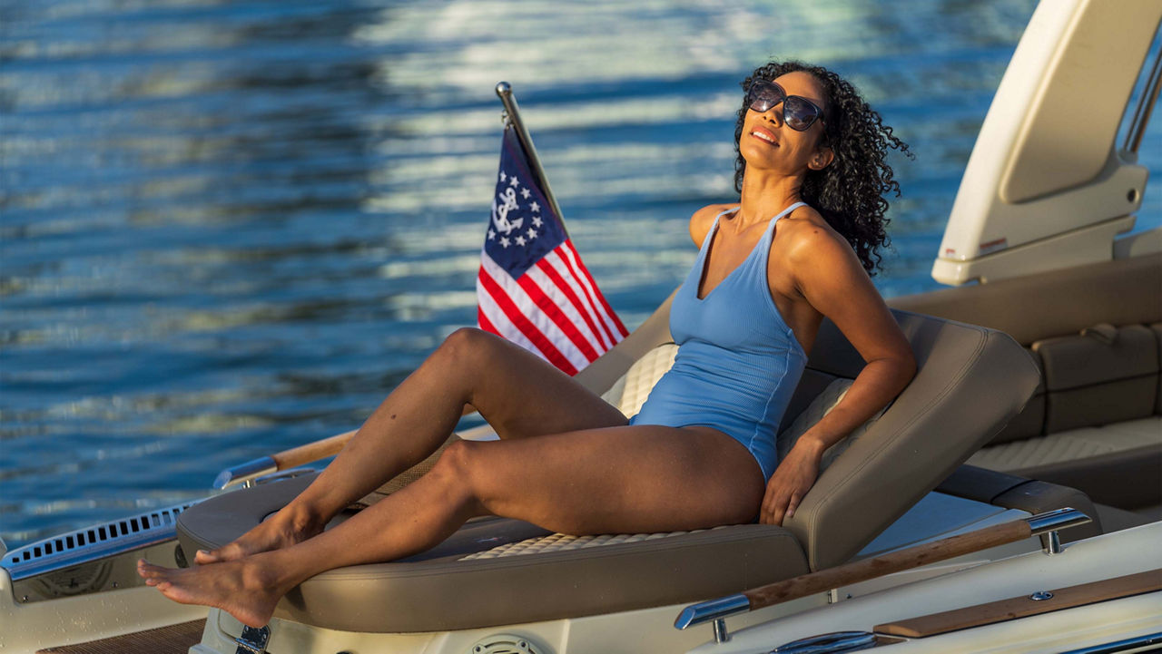 A woman laying on the side of a boat on the water