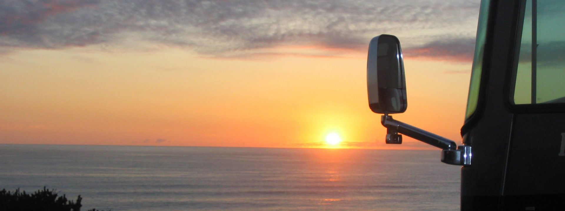 Sunset over the ocean horizon while the RV watches 