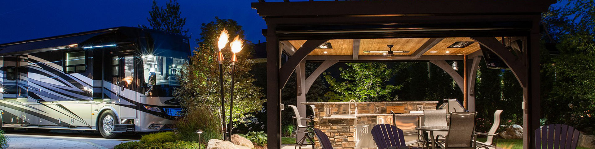 A Newmar RV parked next to outdoor patio with fire pit