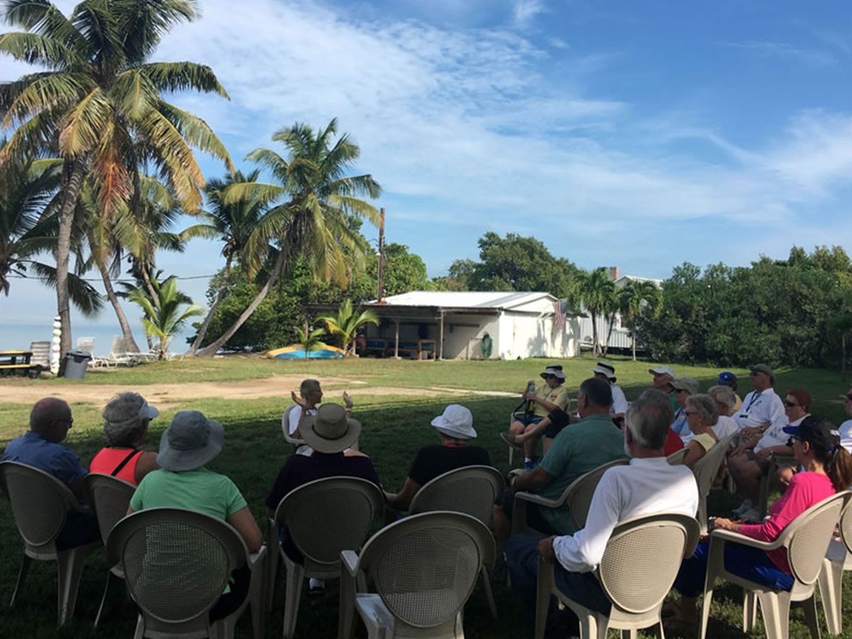 A bunch of folks listening a story in a tropical climate