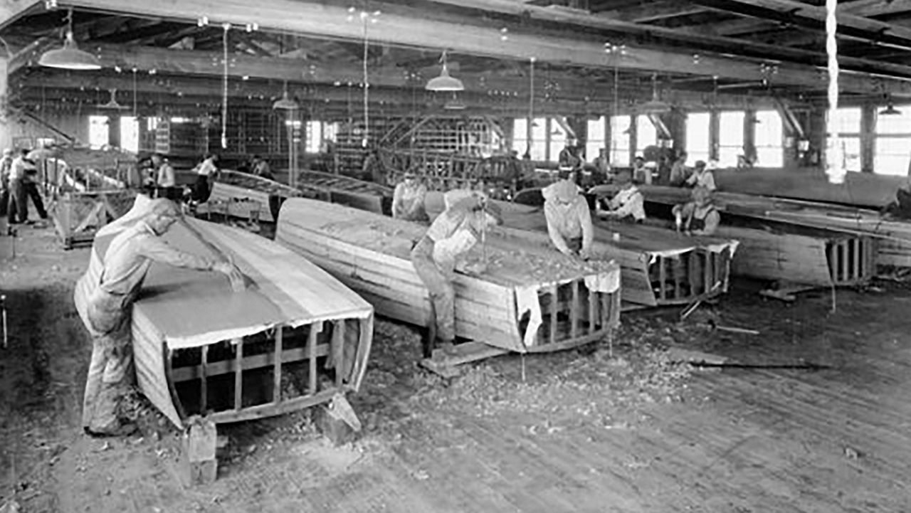 unfinished Chris Craft boats being worked on by employees