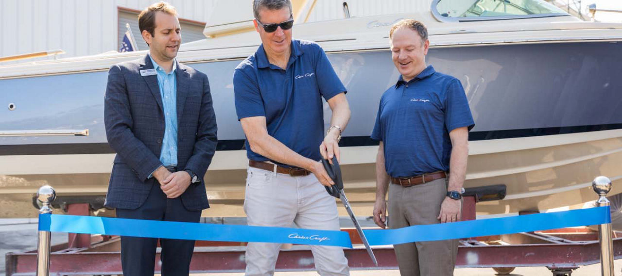 Three men next to each other and one in the middle cutting a ribbon